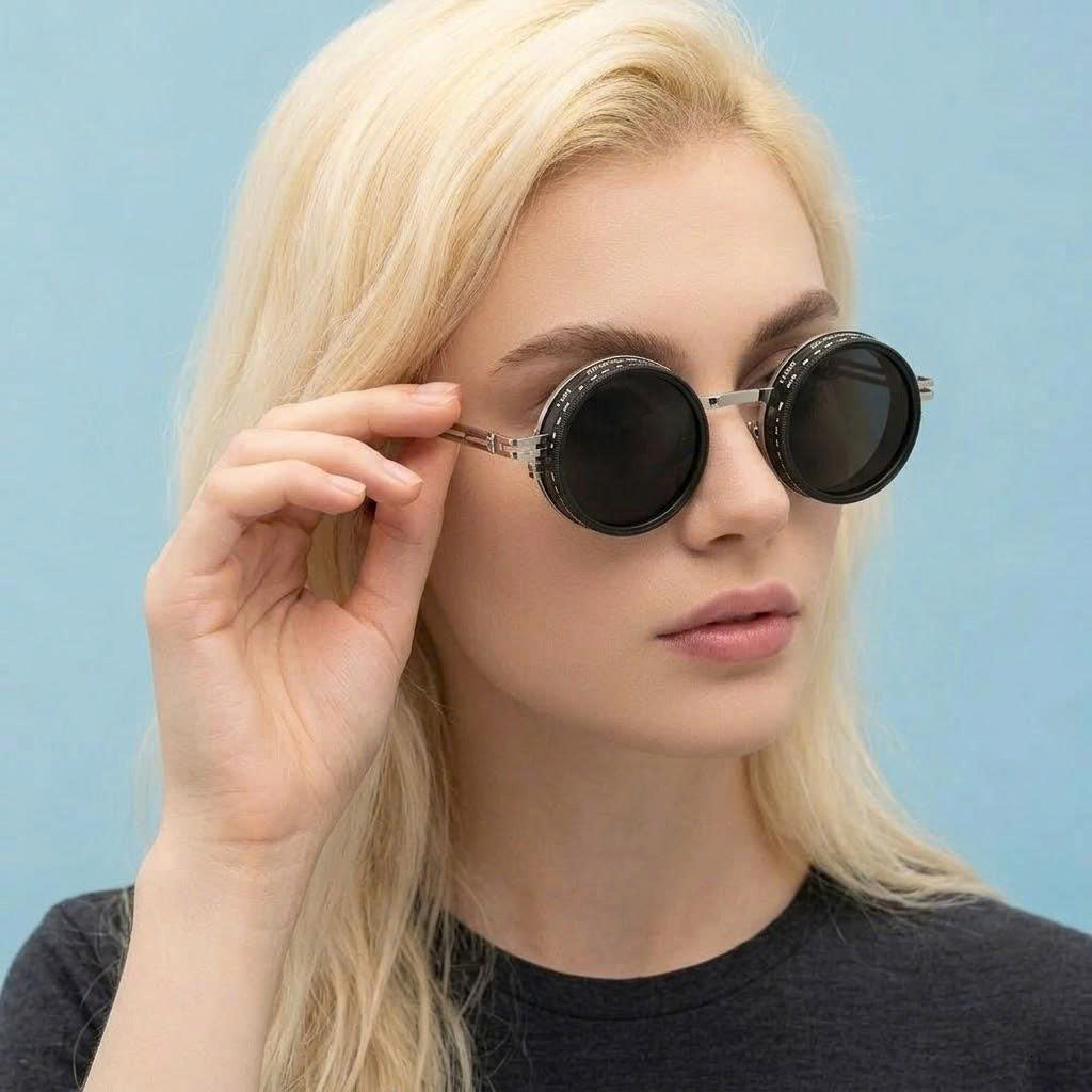 Woman wearing round sunglasses against a light blue background